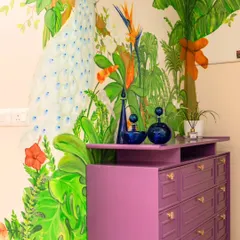 A close-up of the peacock mural, showing the detail in the feathers and the surrounding flora. The purple chest of drawers was chosen to complement the colors in the artwork, creating a cohesive and dramatic entryway.