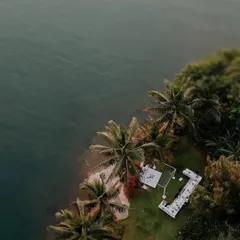 A breathtaking top-down drone shot of an intimate white wedding ceremony by the sea. This perspective highlights the beauty and seclusion of the location.