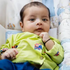 A sweet, direct portrait of a newborn baby looking at the camera while resting comfortably. This photo captures the innocence and charm of a baby's first weeks.