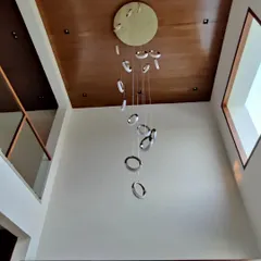 A view from below of the spiral ring chandelier, showing how the individual elements are suspended to create a floating, sculptural effect against the wooden ceiling.