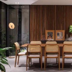 This dining area demonstrates how we use plants to soften modern interiors. A large potted plant is placed by the window, complementing the natural wood and rattan textures of the furniture and creating a warm, inviting atmosphere.