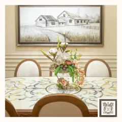 This elegant dining room setting is anchored by a large, 3D wall art piece depicting a country road. Paired with a marble inlay table and a floral centerpiece, it creates a luxurious yet rustic atmosphere.
