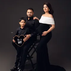 A classic family portrait. The older brother looks so proud, holding an "It's a Boy" sign. It's a beautiful way to announce the gender and include the whole family.