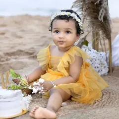A close-up shot of a baby girl curiously touching her first birthday cake during her adorable beach cake smash session.