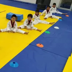 After a rigorous training session, flexibility is key. Our young students work on their splits and stretches, an essential part of Taekwondo that improves range of motion and prevents injury.