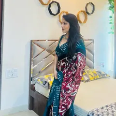 This is a designer saree I created with a bold, abstract print. The deep teal color is complemented by swirls of red and white, making it a piece of wearable art.