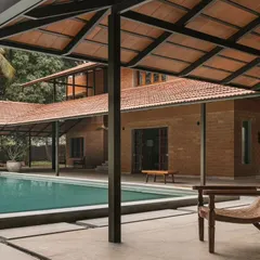 The poolside lounge area at Villa Maati, sheltered by an exposed-beam roof with Mangalore tiles. This space is perfect for year-round outdoor living, connecting the main house with the pool and garden.