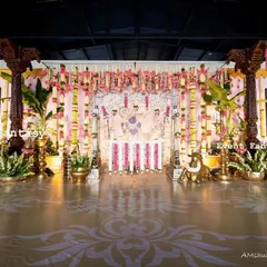 A wide view of a grand stage I designed for a naming ceremony. The decor features traditional carved pillars, a Pichwai art backdrop, and a floor adorned with rangoli patterns, creating a magnificent setting.