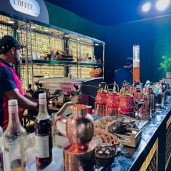 The coffee bar in action, with a barista preparing drinks and a display of elegant copper teapots.