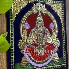 Goddess Lakshmi, sitting on a lotus, smiling upon us and blessing us all with her glory. This finished painting showcases the classic elements of Tanjore art, from the green Kundan stone border to the intricate gold work.