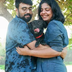 A warm embrace with a furry family member. This outdoor couple's portrait shows the pure love and happiness that pets bring into our lives. Look at that happy tongue lick!