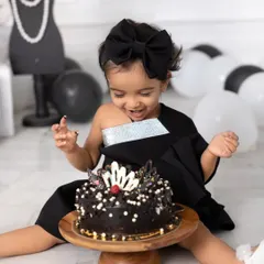 A cake smash with a side of high fashion. This little girl is all smiles as she gets ready to dig into her chic, Chanel-themed birthday cake.