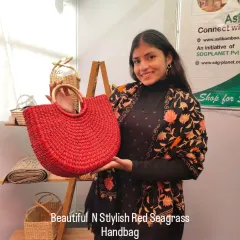 We love adding a splash of color to our sustainable accessories. Here, a customer proudly holds our vibrant red seagrass handbag with a round wooden handle, a perfect statement piece that is both stylish and eco-friendly.