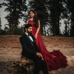 A powerful and elegant couple's portrait. The rich texture and color of the red gown's train spread out on the ground add a touch of formal drama to this outdoor setting.
