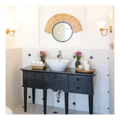 The son's bathroom in this holiday villa is a playful combination of black and white tiles. We designed a custom walnut vanity counter and paired it with a quirky cane mirror to create a space that is both youthful and stylish.