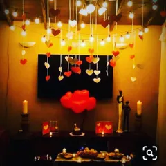 A cozy and intimate anniversary dinner setup at home. I used warm fairy lights, hanging heart cutouts, and candles to create a romantic glow around the television and dining table.