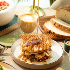 The perfect syrup pour over banana pancakes with a honeycomb wafer. This action shot is dynamic and makes the dish look extra delicious.