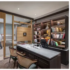 The MD cabin at Jain Cosphere Office, featuring a custom U-shaped desk and a large book cabinet. The material palette of dark wood, Michelangelo stone, and brass inlay creates an atmosphere of minimal luxury.