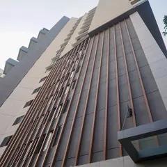 An upward view of the residential tower's façade, showcasing the clean lines of the wooden fins and the building's strong verticality.