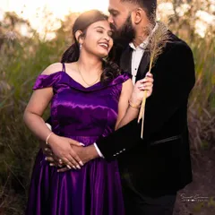 A sweet and romantic moment in a golden field. The groom's classic black velvet blazer perfectly complements the bride's rich purple off-shoulder gown.
