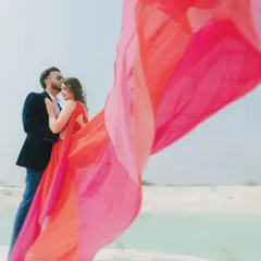 A close-up, artistic shot from a pre-wedding session, with the groom kissing the bride's forehead. The flowing fabric of the gown creates a beautiful, soft frame, highlighting the romance of the moment.