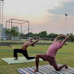 In a beautiful outdoor setting, two movers practice a low lunge variation (Anjaneyasana). This pose is excellent for opening the hips and stretching the chest and shoulders.