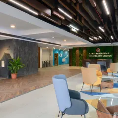 This wide view of the Aarti Research & Technology Center lobby shows how all the elements come together. The design guides you from the entrance past the custom award wall and into the comfortable waiting area, creating a complete brand experience.