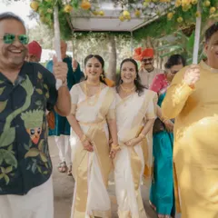 The bride's joyful procession. Pavitra, in her elegant Kerala saree, is escorted by her family, their smiles lighting up the path. This is a moment of pure family love and celebration.