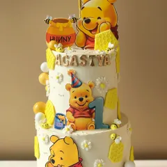A sweet-as-hunny Winnie the Pooh cake for a first birthday. This two-tiered design is decorated with Pooh and his honey pots, perfect for a classic and heartwarming theme.