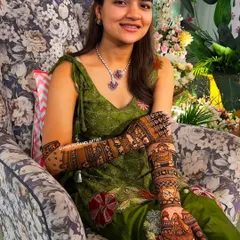 A happy bride proudly displaying her full-arm mehandi for the camera.