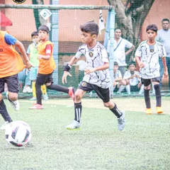 A player driving forward with the ball during an intense match. This shows the attacking mindset we encourage in our players.