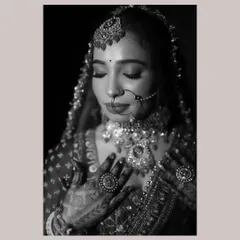 A timeless black and white bridal portrait. This shot emphasizes the bride's serene expression and the intricate details of her jewelry and henna-adorned hands.