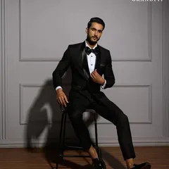 The essence of black-tie sophistication, captured in a seated portrait. This view highlights the perfect fit across the shoulders and the clean lines of the jacket, even at rest.