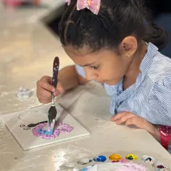 A young artist completely focused on her butterfly texture painting. Our workshops are for all ages, providing a space for kids to explore their creativity with palette knives and thick paints.