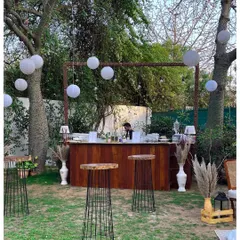 A view of the outdoor event space, showing the custom wooden bar in the background and the relaxed lounge seating in the foreground. The entire setup is designed to feel cohesive and inviting.
