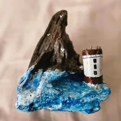 A work-in-progress shot of a driftwood piece. Here, a tiny lighthouse sits on a sculpted wave, waiting for its final details. This is the blank canvas stage of our creative process.