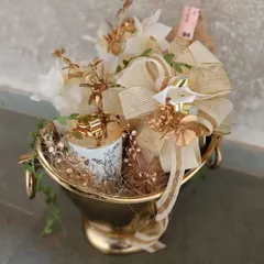 A close-up of our champagne bucket hamper, highlighting the intricate details of the golden floral accents and the elegantly placed candle, all coming together to create a gift of pure opulence.