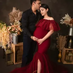 A romantic couple's maternity portrait. The rich red gown stands out beautifully against the moody background, creating a striking and passionate image.