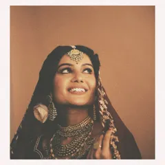 A portrait of vintage bridal beauty. This bride's look is defined by exquisitely layered polki and pearl jewelry, a traditional matha patti, and a rich maroon and gold ensemble that evokes old-world royal charm.