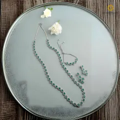 A simple yet stunning single-strand necklace made with green American diamonds, complete with a matching bracelet and earrings. This set is perfect for a minimalist, modern look.