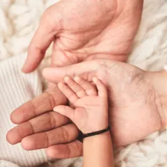 A baby's hand resting in the palms of their parents, showing the scale of new life.