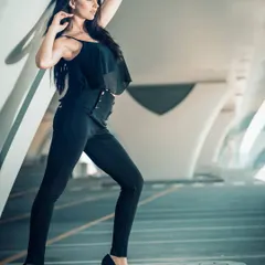 Shot in a modern, architectural setting, this image uses leading lines and dramatic lighting to create a sophisticated mood. The all-black outfit stands out, conveying a sleek and powerful style.