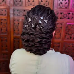 This textured bun is created by weaving multiple braids together. The geometric accessories add a modern touch to a classic updo.