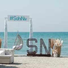A relaxed, bohemian beach setup for a pre-wedding event in Bahrain. We created a cozy atmosphere with a custom hashtag sign, a hanging swing chair, and neutral-toned decor, perfect for a sundowner.
