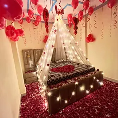 I create truly romantic and memorable experiences. This bedroom decoration features a beautiful canopy with fairy lights, hundreds of red balloons, and a floor covered in rose petals for the perfect surprise.