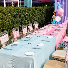 The kids' dining table was set up with alternating pink and blue tablecloths. The chairs were decorated with custom sashes, continuing the whimsical Disney theme down to the smallest details.