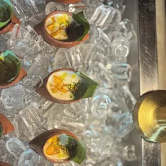 To ensure my chilled desserts are served at the perfect temperature, I present them on a bed of ice. Here, individual portions of Mango Lacha Rabdi are kept cool and refreshing for guests.