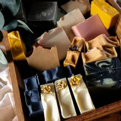 This wooden box is filled with a variety of my hand-poured, hand-cut soaps. From the dark charcoal swirls to the bright yellow turmeric and delicate botanical tops, each bar is a testament to the beauty of natural, plant-based ingredients.