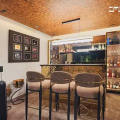 This stylish home bar is perfect for entertaining, with a textured gold-finish bar counter, comfortable bar stools, and glass-fronted cabinets to display a collection of spirits.