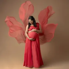 Embracing the goddess within. This portrait showcases the power and beauty of motherhood, using a flowing red gown and soft fabric to create a sense of dreamy elegance for a maternity photoshoot.